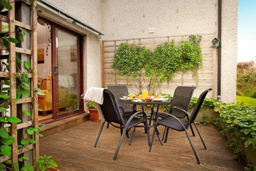 a patio with a table and chairs on a deck at Beechwood Lodge in Alness