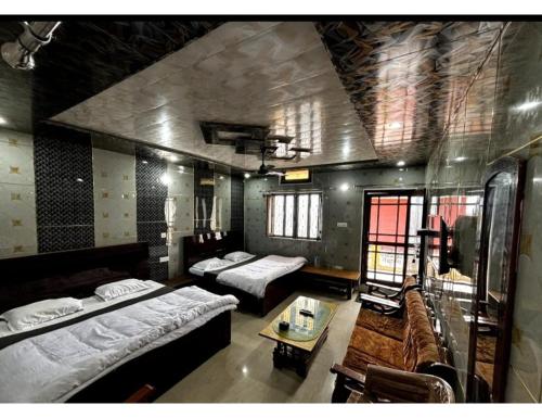 a living room with two beds and a table at Anu Shree Lodge, Ukhimath in Ukhimath