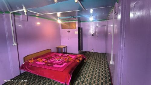 a small room with a bed in a purple room at Gulmarg Hut in Gulmarg