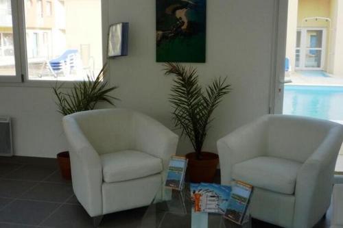 two chairs and a coffee table in a living room at Residence Les Isles de Sola Grandcamp Studio in Grandcamp-Maisy