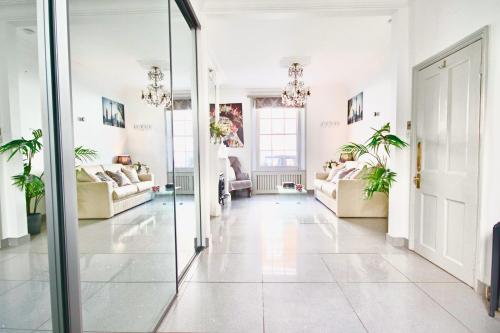 een woonkamer met witte muren en een glazen deur bij Victoria Belgravia Townhouse in Londen