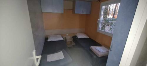 a small room with two beds and a window at Mobil Home 3 chambres 6 pers 1/2h PUY du FOU in La Boissière-de-Montaigu