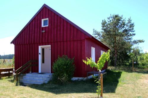 um celeiro vermelho com uma porta branca num campo em Holiday house at the Vilzsee Mirow em Diemitz