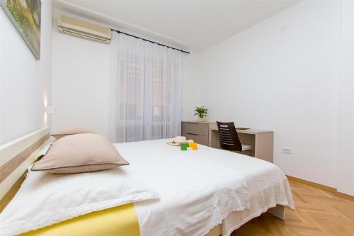 a white bedroom with a bed and a desk at Apartment Marija in Krilo
