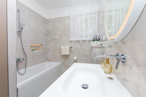 a white bathroom with a tub and a sink at Apartment Marija in Krilo