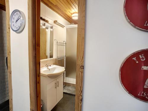 La salle de bains est pourvue d'un lavabo et d'une horloge murale. dans l'établissement Montana - appartement - 6pers - proche centre, aux Gets