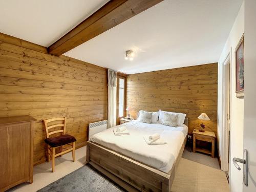 une chambre avec un lit et un mur en bois dans l'établissement La Parisienne - appartement- 6pers- Centre, aux Gets