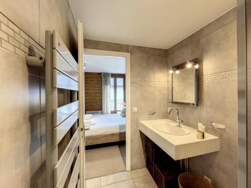 La salle de bains est pourvue d'un lavabo et d'un lit dans la chambre. dans l'établissement La Parisienne - appartement- 6pers- Centre, aux Gets