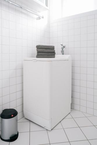 a white tiled bathroom with a counter with towels on it at Lüttje Nest in Norderney