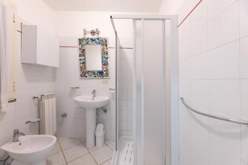 a white bathroom with a sink and a toilet at Villino Straccoligno - Goelba in Capoliveri