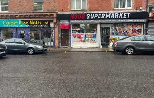 two cars parked in a parking lot in front of a store at Studio Flat 7 With Private Shower & WC in Nottingham