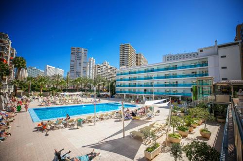 a pool in a city with people sitting around it at Hotel Servigroup Calypso in Benidorm