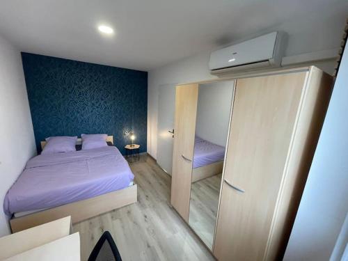 une petite chambre avec un lit violet et un miroir dans l'établissement Appartement T3 avec jardin et véranda, à Saint-Priest