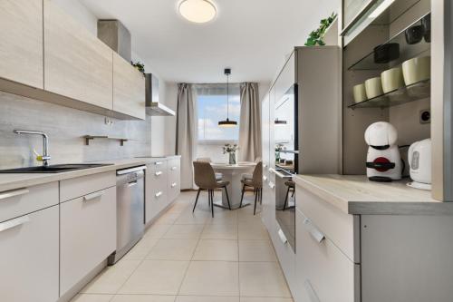 a kitchen with white cabinets and a table with chairs at LAM City Jungle - SKY VIEW 21 FLOOR - Free Parking in Bratislava