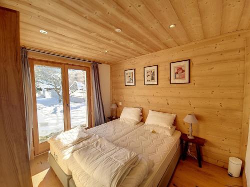 une chambre avec un lit dans une cabane en rondins dans l'établissement Chalet Framboisiere - 10 pers - proche piste, aux Gets