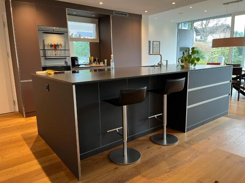 a kitchen with a black island with bar stools at Casa Casparis in Maienfeld