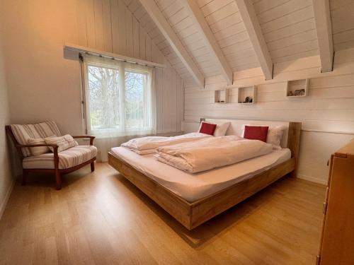 a bedroom with a large bed and a chair at Wine Tours Lodge in Maienfeld