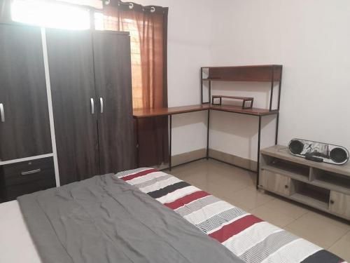 a bedroom with a bed and a desk and a shelf at Jay's Apt in Takoradi