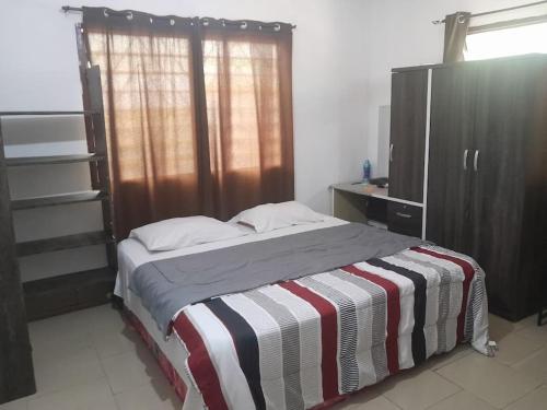 a bedroom with a bed with a striped blanket at Jay's Apt in Takoradi