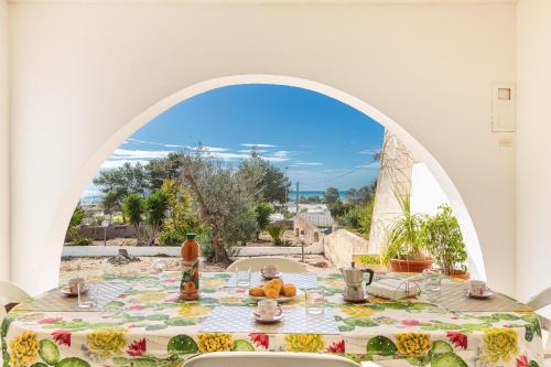 a table with a view of the ocean from an archway at Salentoandmore - Villetta Anna in Marina di Pescoluse