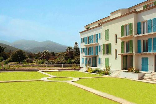 um grande edifício com um jardim de relva em frente em Res Villa Tyrrenia Macinaggio Rogliano Apartment with bay view em Macinaggio