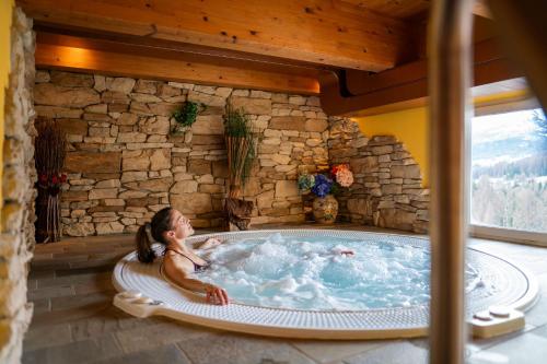 Hotel Des Alpes في كورتينا دامبيتزو: امرأة تجلس في حوض استحمام ساخن في المنزل