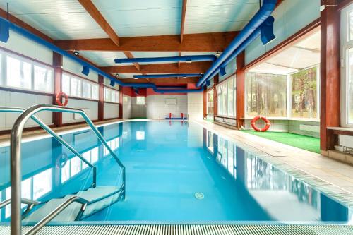 a swimming pool with blue water in a building at Hotel Bocianie Gniazdo in Niechorze