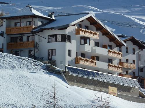 ein Gebäude auf einem schneebedeckten Hang in der Unterkunft Chasa Sulai Appartements in Samnaun