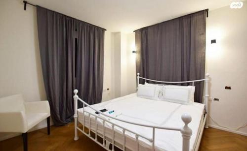 1 dormitorio con cama blanca y ventana en אחוזת פרישמן, en Herzliya