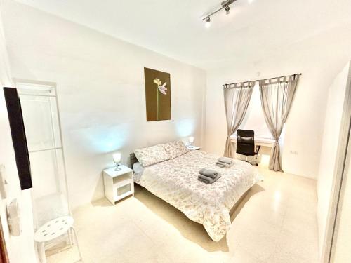 a white bedroom with a bed and a chair at St Julians - Balluta Bay large 3 bedroom apartment in Sliema