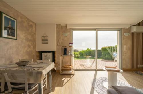 une cuisine avec une table et une grande porte coulissante en verre dans l'établissement La grande côte face océan, à Saint-Palais-sur-Mer