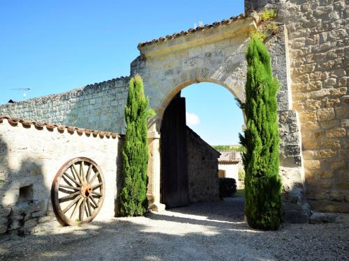 un arco en un edificio de piedra con una rueda de madera en Castle 12th century with private pool close to Agen, en Saint-Caprais-de-Lerm