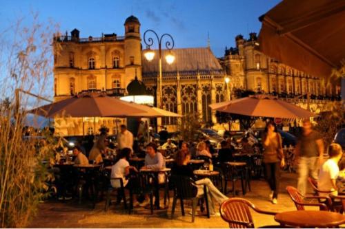 um grupo de pessoas sentadas em mesas em frente a um edifício em Charmant studio au Pecq / Saint-germain en laye. em Le Pecq