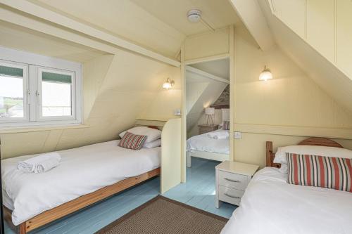 a room with two beds and a window at Cable Cottage in Llanrhyddlad