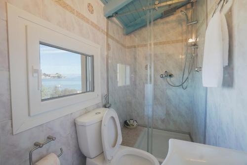 a bathroom with a toilet and a shower and a window at Anemomilos Sea View Penthouse in Corfu Town
