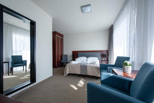 a hotel room with a bed and two blue chairs at Apartamenty przy Latarni in Niechorze