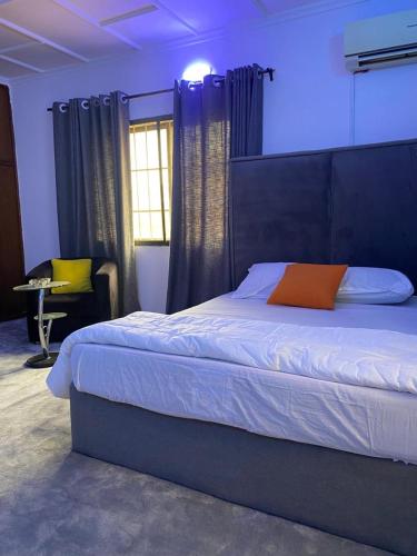 a bedroom with a bed with an orange pillow on it at Kath's Hub in Lagos