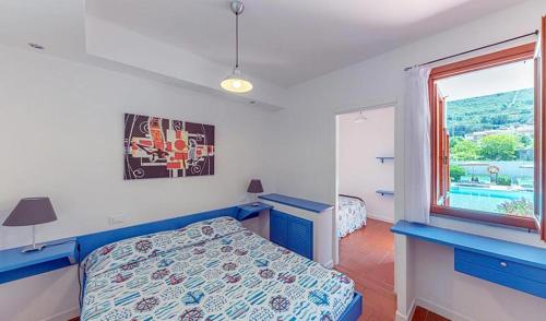 sypialnia z niebieskim łóżkiem i oknem w obiekcie Elba Island Resort Pool & Tennis w mieście Nisporto