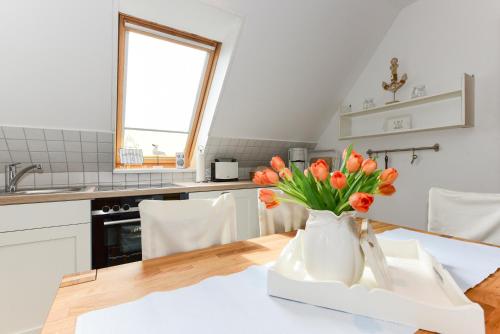 een keuken met een tafel met een vaas met oranje bloemen bij Haus Bonken - a72764 in Wyk auf Föhr