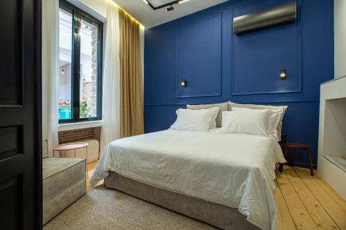 a bedroom with blue walls and a bed with white sheets at Stoa House Airport in Koropi