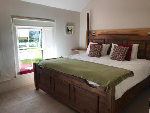 um quarto com uma grande cama de madeira e uma janela em Gortamullen House, Kenmare em Kenmare