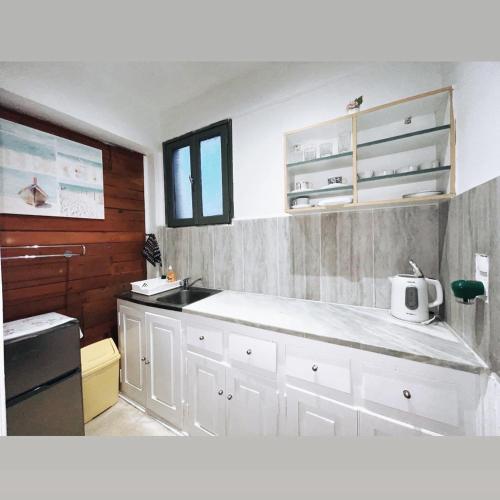 a kitchen with white cabinets and a counter top at VILLA MARIA (2) in Paleokastritsa