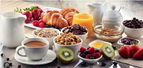 einen Frühstückstisch mit Frühstückszutaten sowie Kaffee und Obst in der Unterkunft B&B Nouveauté in Vaals