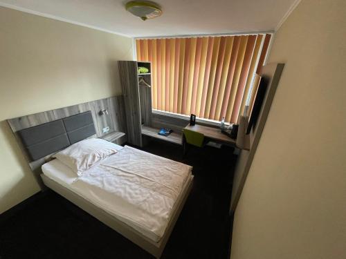 a small bedroom with a bed and a window at Hotel Am Sportpark in Duisburg