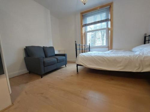a bedroom with a bed and a chair and a window at Newly refurbished studio in London