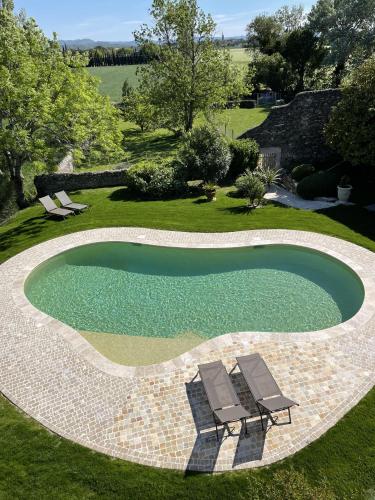 a swimming pool with two chairs in a yard at Mas de JANNE in Cléon-dʼAndran