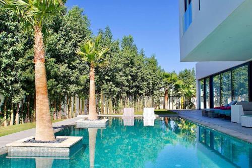 a swimming pool with two palm trees next to a house at Palais Thami in Marrakech