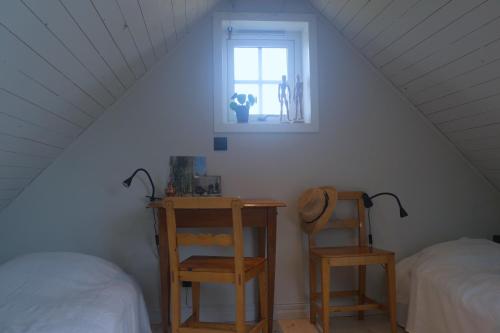 um quarto no sótão com uma cama, uma mesa e uma janela em Loft Apartment at Isola Gård on the middle of Öland em Färjestaden