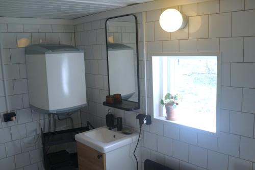 uma casa de banho com um lavatório, um espelho e uma janela em Loft Apartment at Isola Gård on the middle of Öland em Färjestaden