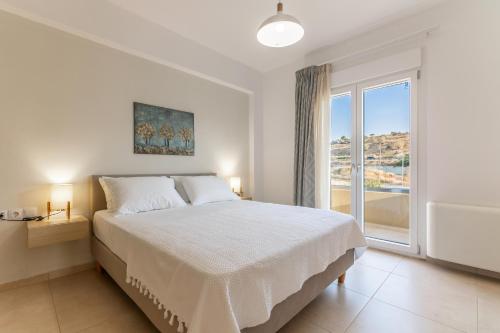 Un dormitorio blanco con una cama y una ventana grande. en Villa Carpe Diem - 2BR - 300m to Beach, en Heraklion